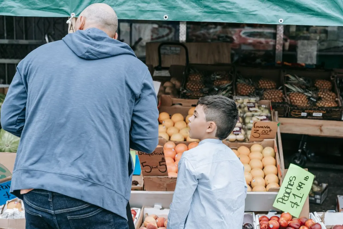Father and son explore a bustling farmer's market filled with fresh produce. - Photo by Timur…