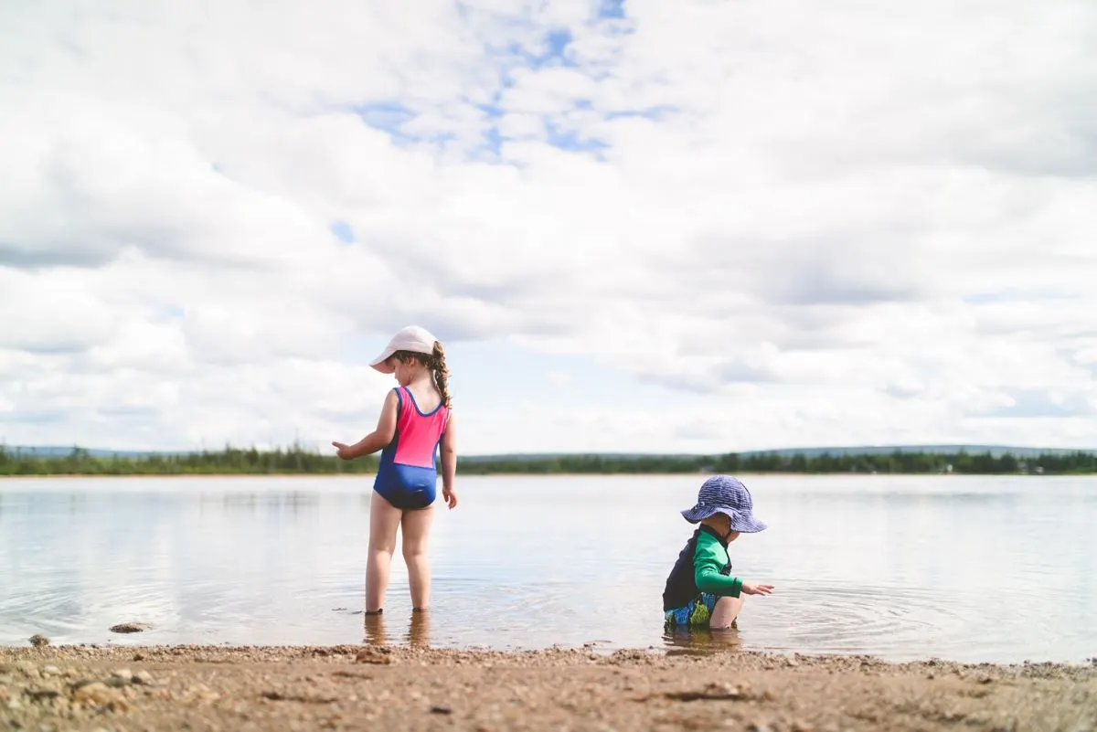 Two kids enjoy playing by the water at the beach under a cloudy sky. - Photo by Stephen Andrews…